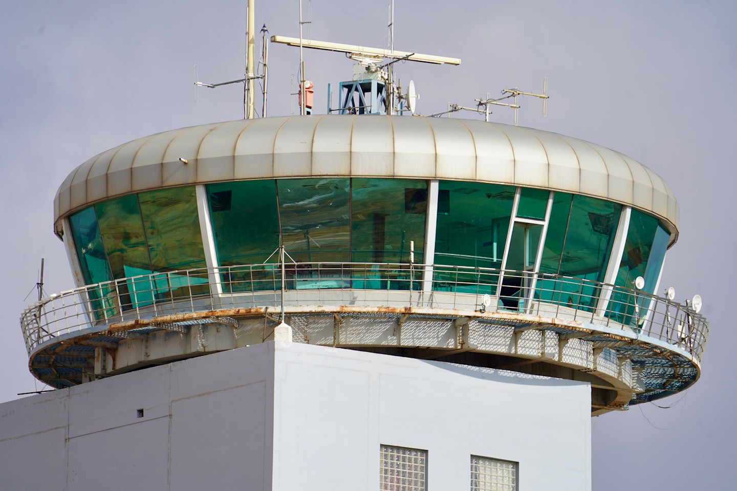White concrete control tower with antennas and radar dish.