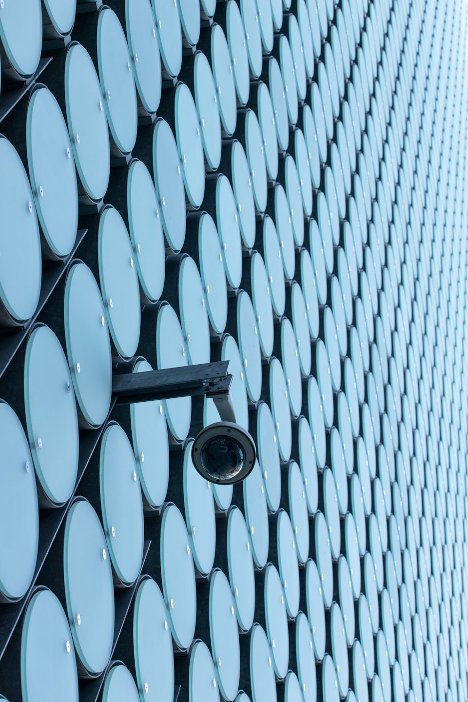 Security camera mounted on a building facade with blue circular panels.